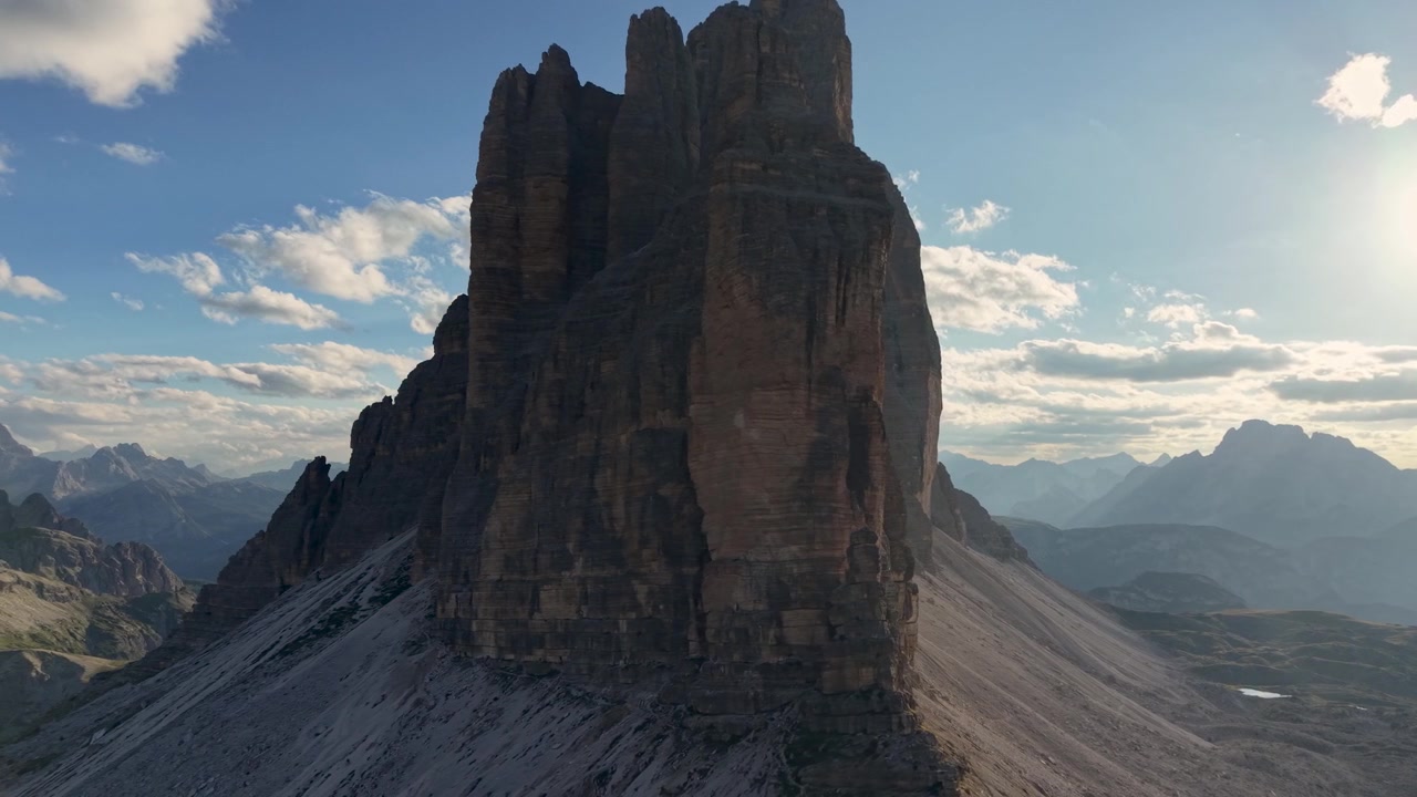 Slow orbital drone shot circling the iconic Tre Cime di Lavaredo during golden hour in the Dolomites, Italy