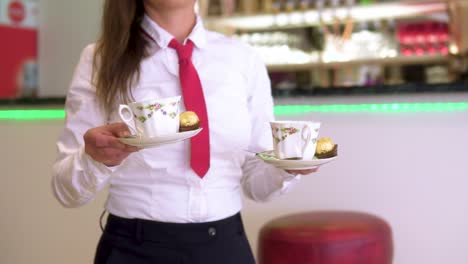 smart dressed waitress serving guests with cup of coffee and bar in the backround in music instruments restaurant slow motion