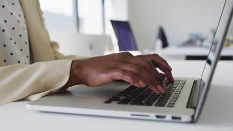 close up of hands of african american businesswoman typing on laptop
