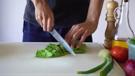 manos cortando lechuga fresca con un cuchillo de metal en la tabla de cortar - de cerca