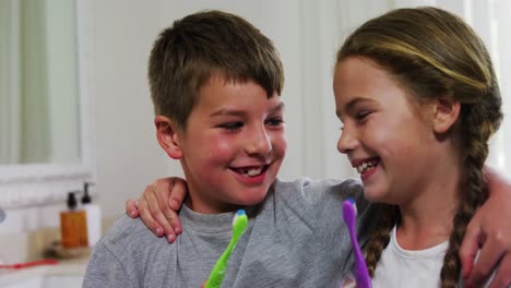 hermanos sosteniendo su cepillo de dientes en el baño 4k