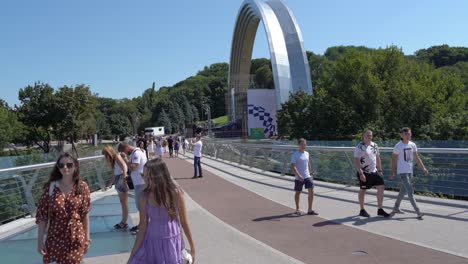 people walking on a modern arch bridge