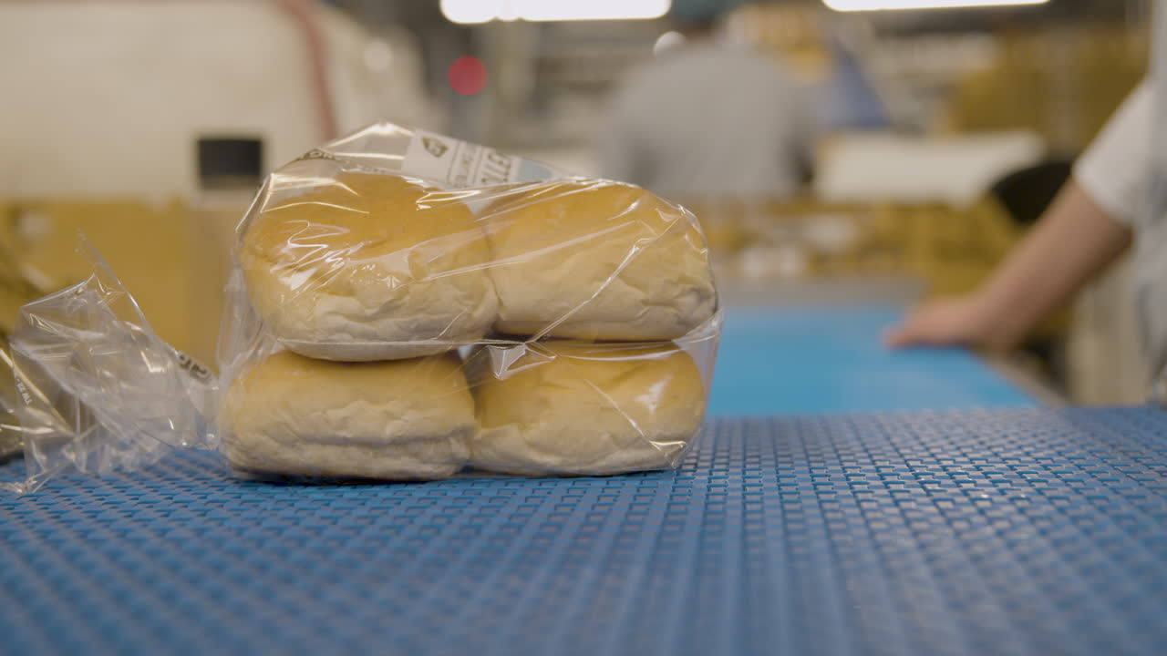 작업자가 집어 들고 있는 컨베이어에 있는 비닐 봉지에 빵 빵