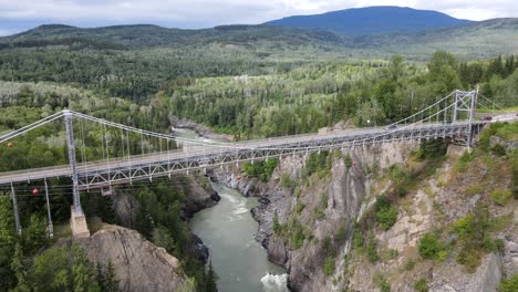 4k aerial footage of orbiting camera movement around hagwilget canyon bridge crossing skeena river in british columbia