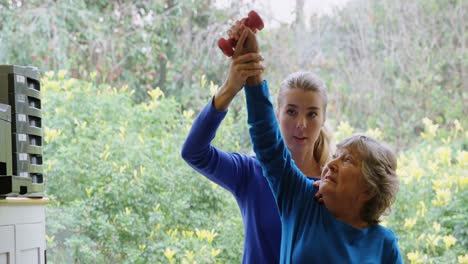 Physiotherapist-giving-shoulder-therapy-with-dumbbell-to-senior-woman-4k