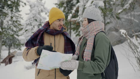 couple looking at a map in snowy mountains