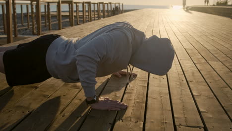 man doing push-ups on a wooden pier at sunrise/sunset