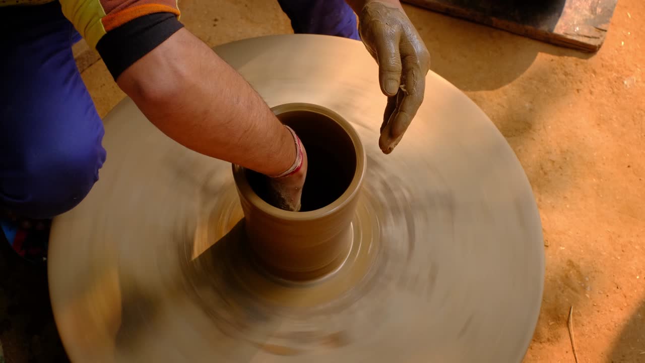 Pottery - skilled wet hands of potter shaping the clay on potter wheel. Pot, vase throwing. Manufacturing traditional handicraft Indian bowl, jar, pot, jug. Shilpagram, Udaipur, Rajasthan, India