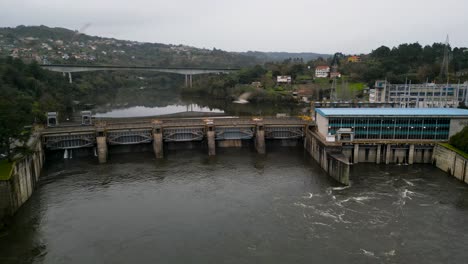 Panorámica-Lenta-A-Través-De-La-Presa-De-Agua-Mientras-Los-Pájaros-Vuelan-Frente-A-La-Presa-De-Agua-Velle-Y-La-Central-Eléctrica-En-Ourense,-Galicia,-España.