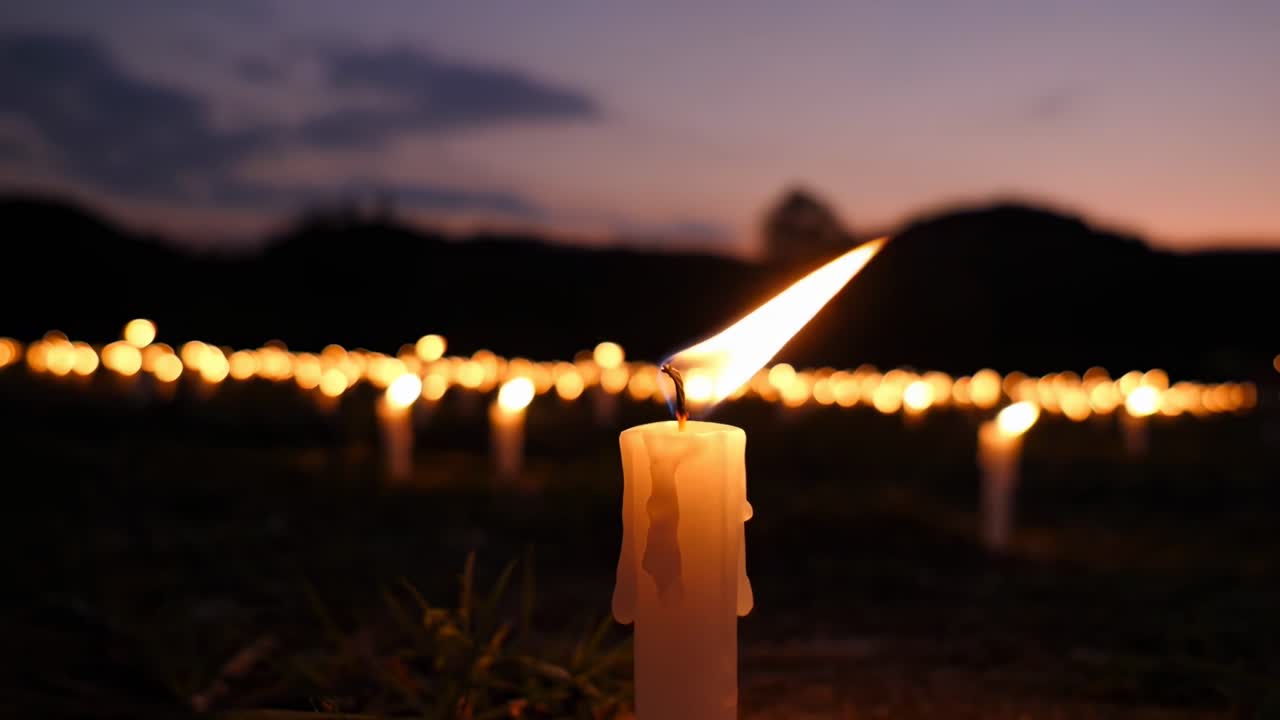 Video con inquadratura dal basso di candele accese al crepuscolo, creando un'atmosfera serena e tranquilla.