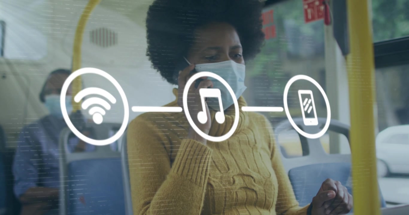 Animation of phone icons in circles over african american woman wearing mask using phone in bus