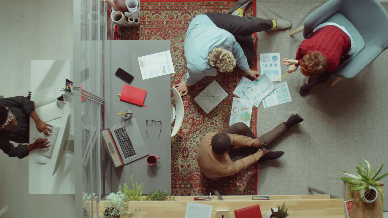 compañeros de trabajo sentados en el piso en la oficina y discutiendo el proyecto de negocio
