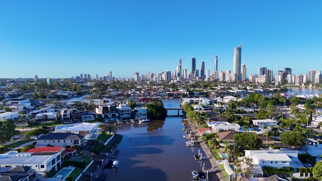 Drone footage captures Gold Coast's urban skyline and tranquil river, highlighting vibrant architecture and lush greenery under clear blue skies