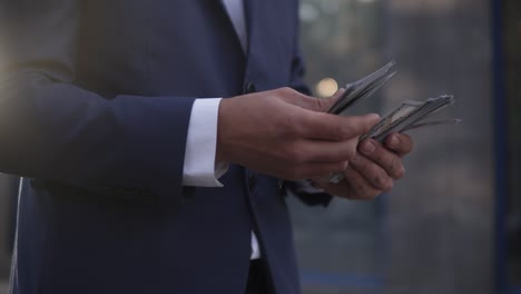 Unrecognizable-Businessman-On-The-Street-Holding-Bundle-Of-American-Money-In-His-Hands,-Counting-It