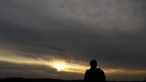 young adult man gazes at vast sunset contemplating life. self-exploration concept