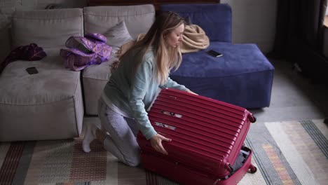 Woman-closing-and-zipping-suitcase,-getting-ready-for-road-trip-preparing-luggage-for-vacation-in-a-living-room