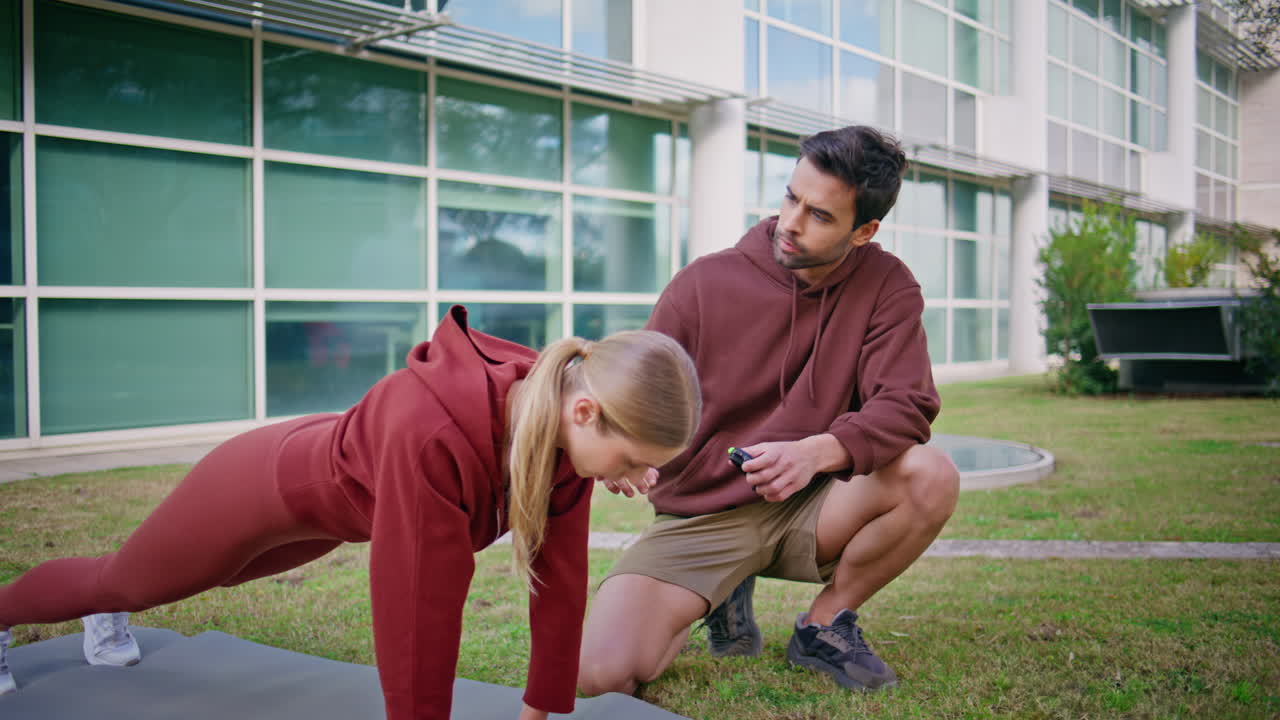 Athletic girl plank position training outdoors. Professional coach assisting
