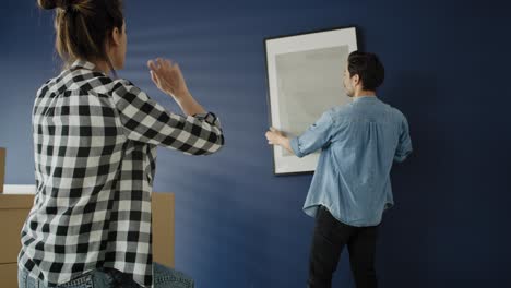 video of couple hanging a picture frame on the wall.