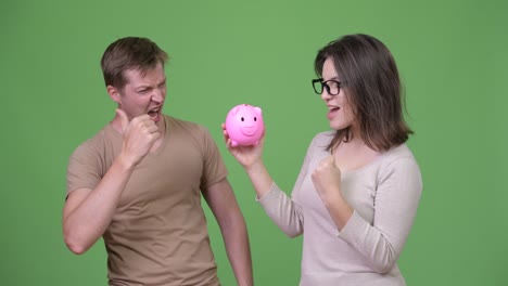 young couple holding piggy bank and giving thumbs up together