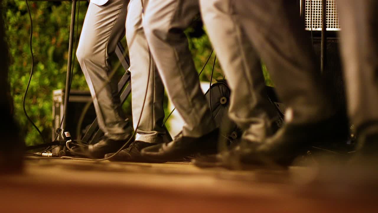toma en ángulo bajo de tres miembros de la banda bailando juntos en perfecta sincronización en el escenario