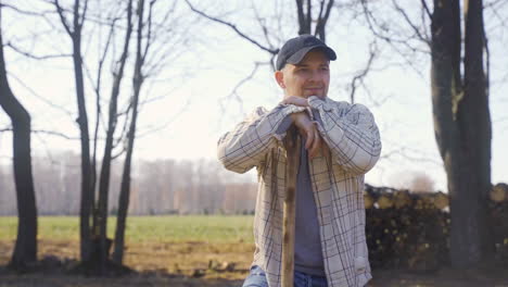 caucasian man leaning on the stick of a rake and talking with other person in the countryside