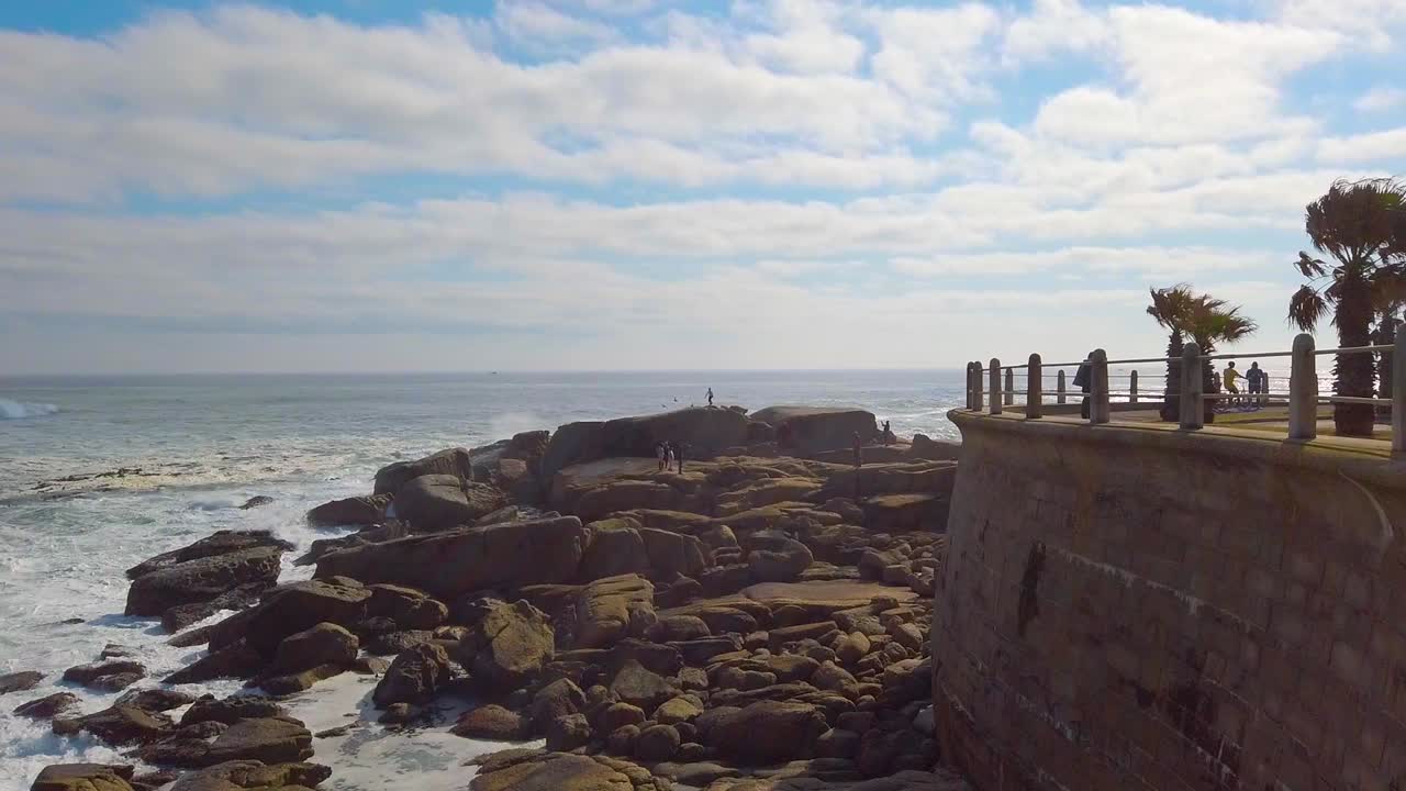 파도가 바위에 부서지는 바다 지점 산책로를 가로지르는 슬로우 모션 팬