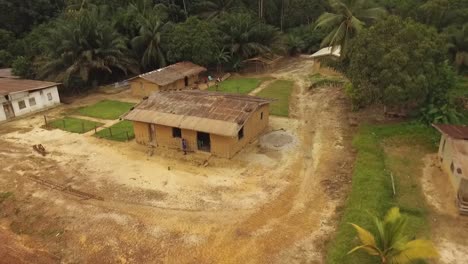 aerial view of houses near dirt road, surrounded by trees in kribi in cameroon, west africa