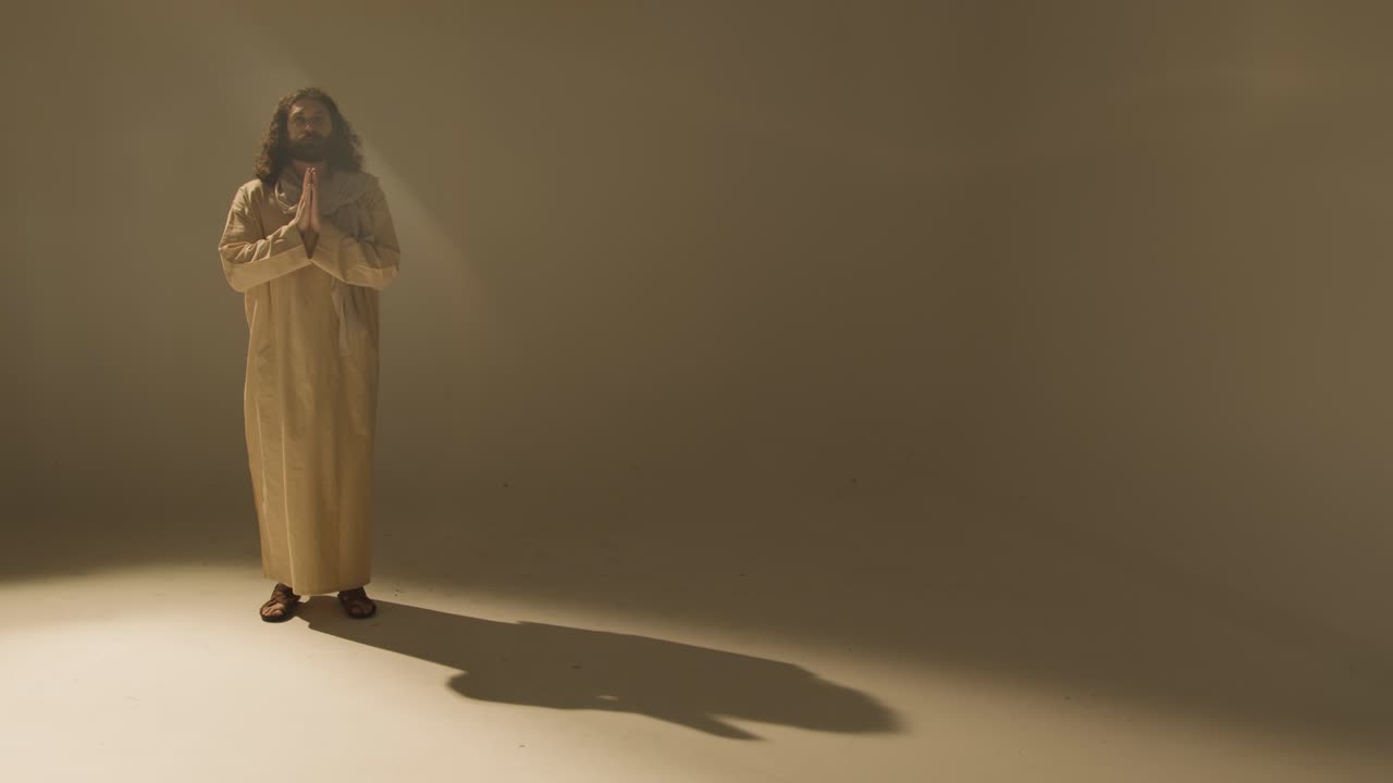 Full Length Studio Portrait Of Man Wearing Robes And Sandals With Long Hair And Beard Representing Figure Of Jesus Christ Praying 1