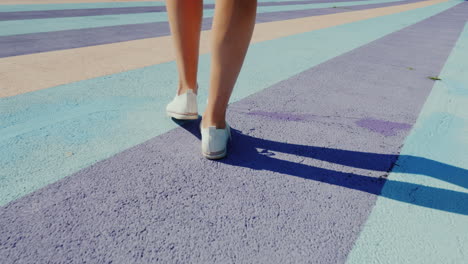 follow shot of walking feet in sports shoes walking on colorful motley asphalt