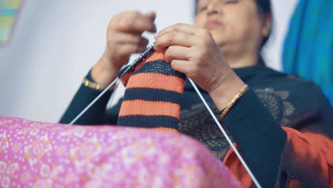 Woman-knits-scarf-with-craft-needles-and-red-and-black-wool