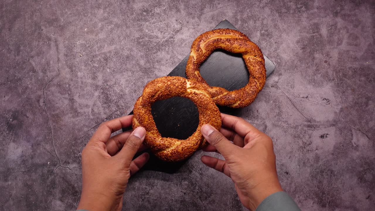 Hands holding a Turkish simit bagel