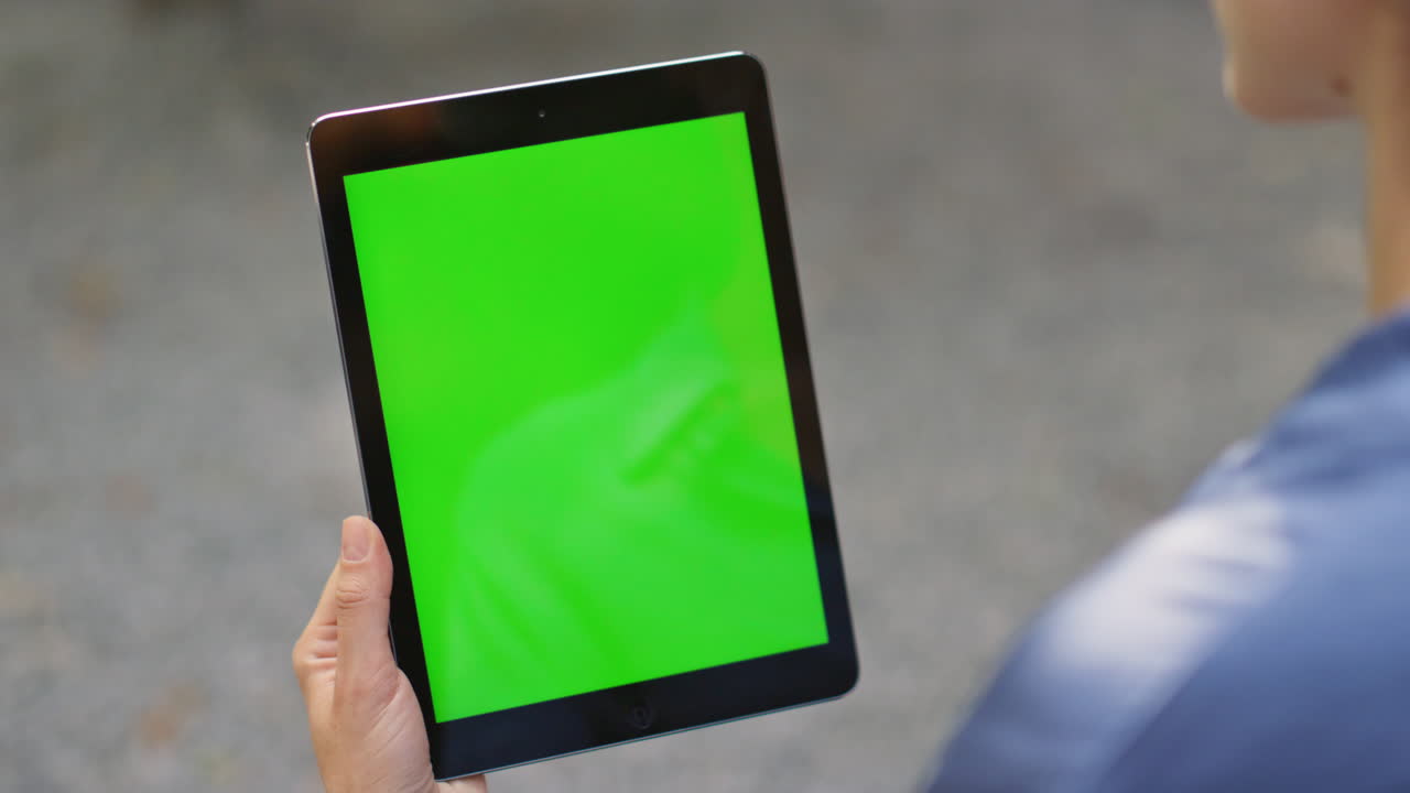 손으로 태블릿을 들고 있는 크로마 키 모형 야외 클로즈업. 디지털을 찾는 여성