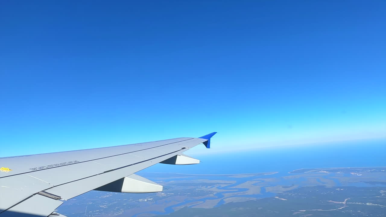 澄み切った青空の下、詳細な都市の風景の上空を飛ぶ飛行機からの眺め。旅行や航空コンテンツに最適