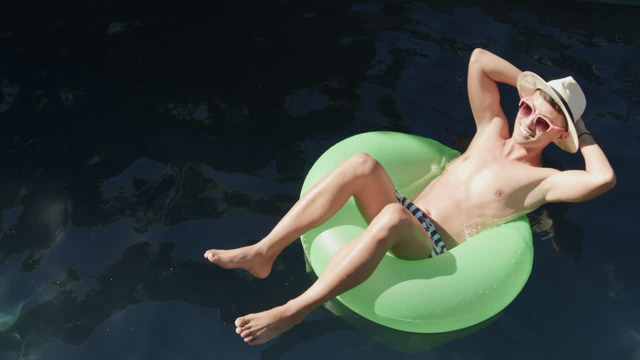 Young Asian man enjoys a relaxing day floating in a pool, with copy space