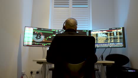 hombre calvo analizando las tendencias del mercado de valores en múltiples monitores en una habitación oscura, iluminado por pantallas