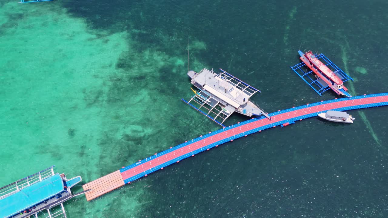 Top-down aerial of Boracay floating pier with boat in crystal-clear turquoise waters. Perfect for travel, maritime, and tropical paradise projects