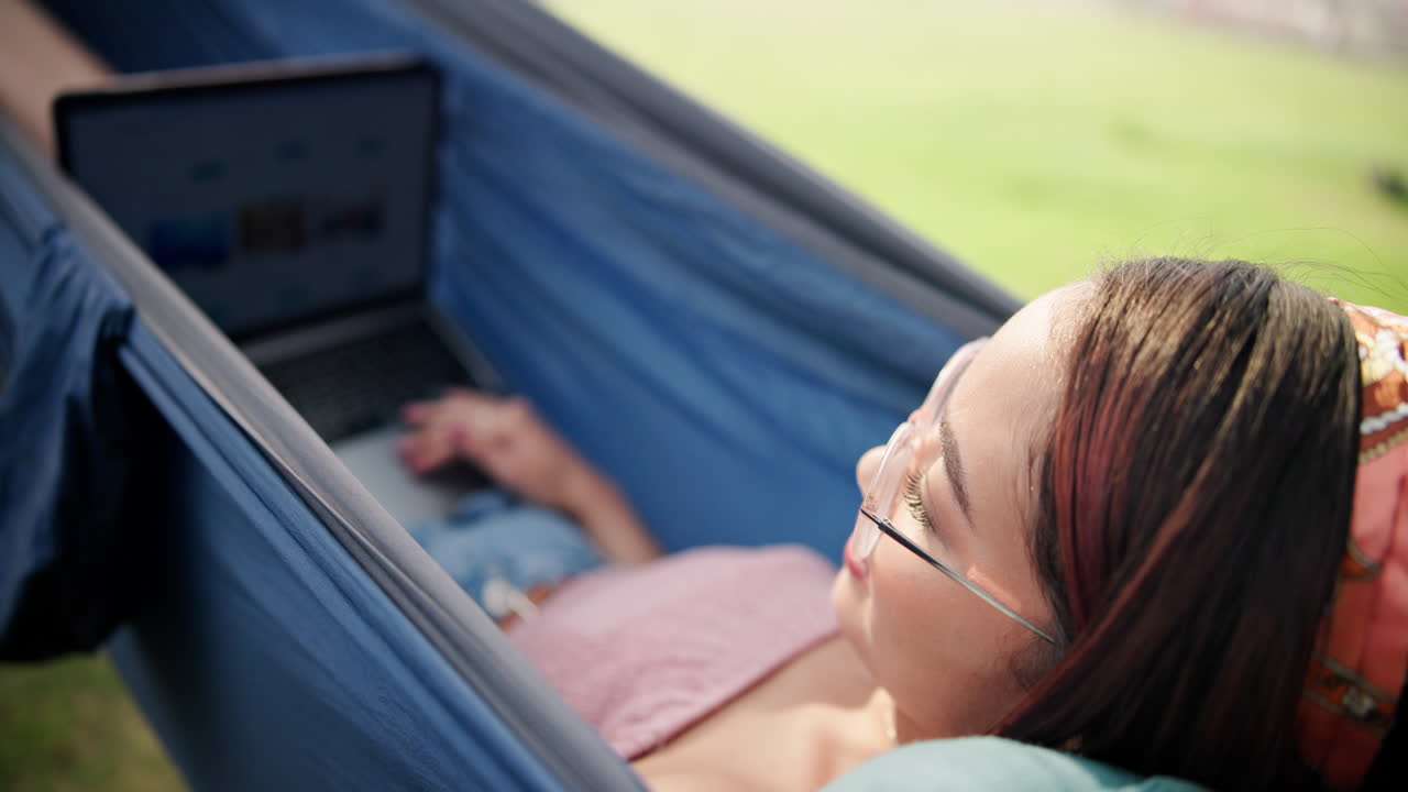 Woman relaxing in a hammock with a laptop