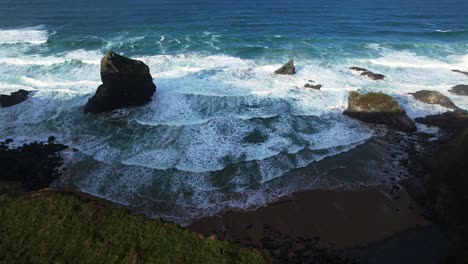 Tilt-Down-Shot-Over-Bedruthan-Steps-and-Ocean-Waves-Along-Beach-in-Cornwall-with-an-Aerial-Drone