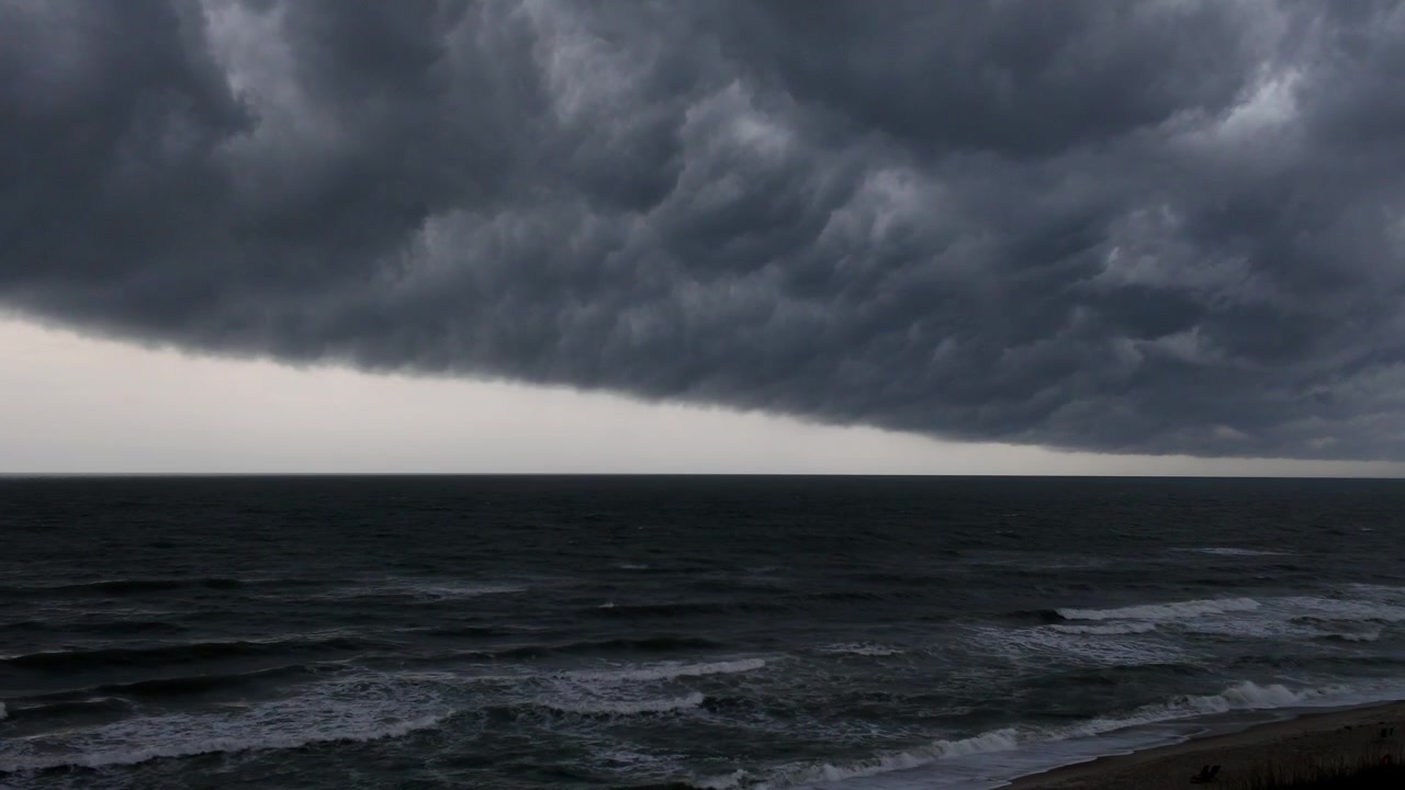 Una potente tempesta oceanica si avvicina alla costa sotto nuvole scure, mostrando condizioni meteorologiche turbolente e un cielo minaccioso