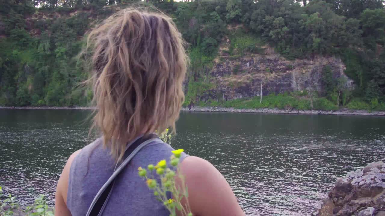 una linda chica hip entra en el marco y mira hacia el agua