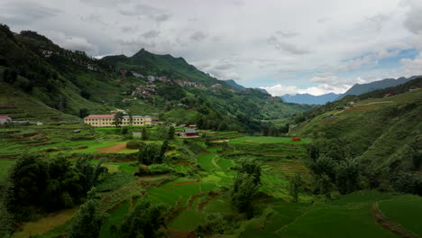 drone establishing dolly over sapa valley terraced agricultural landscape with large buildings and farm houses along hillside