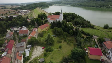 aerial wide orbit over an old church located on the hill over the water dam and antiflood reservoir