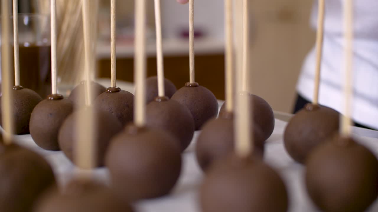 mujer poniendo un palo de madera en una bolita de chocolate para hacer cakepops