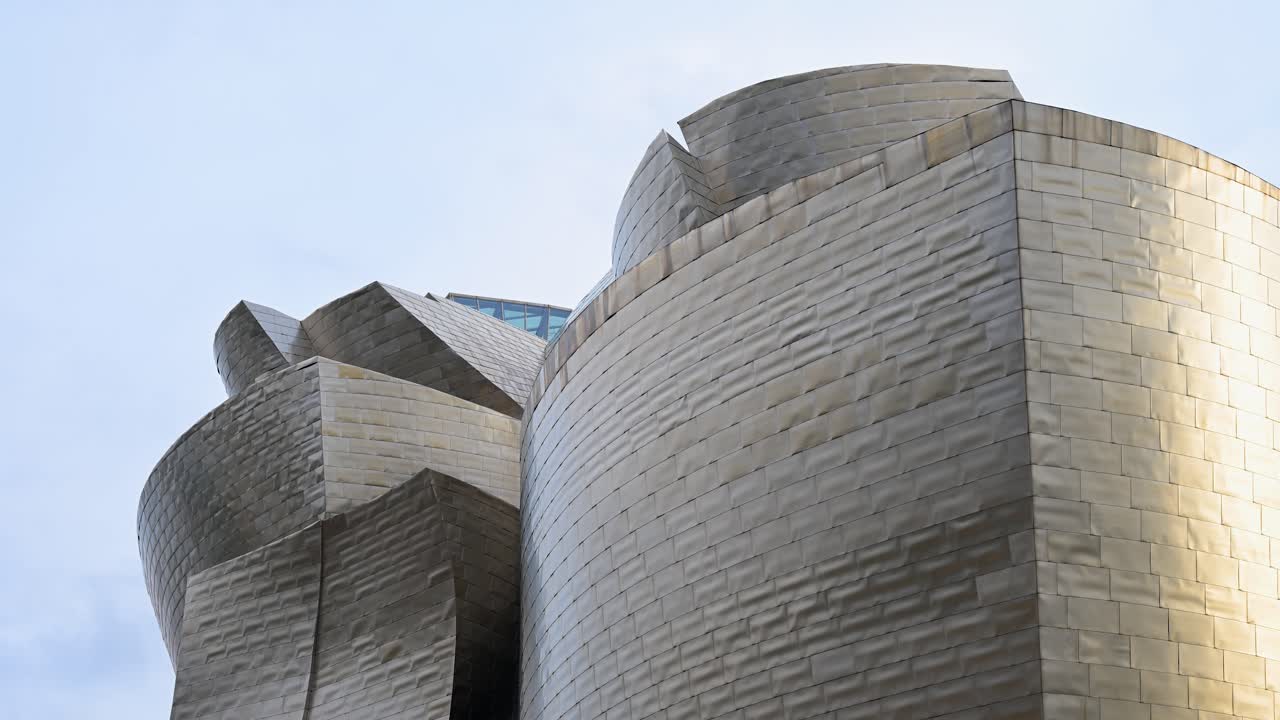 The Guggenheim Bilbao Museum’s reflective stainless steel panels contrast with the sky, highlighting Frank Gehry’s dynamic architecture.