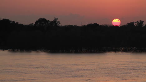 wide shot sun setting over a river from the pov from a cruise ship