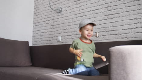 happy energetic toddler boy jumping on the sofa. funny kid having fun playing at home.