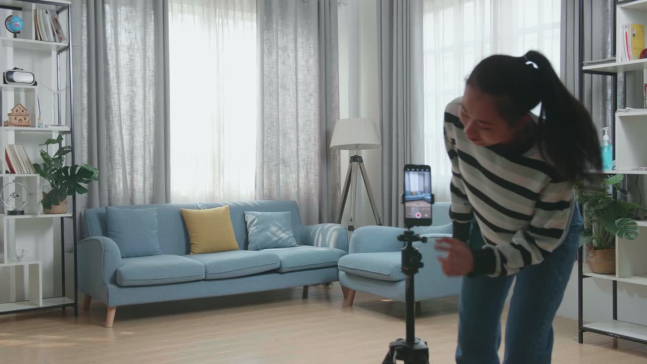 Donna asiatica che balla mentre gira contenuti video per i social network con la fotocamera di uno smartphone