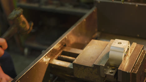 Caucasian-male-hands-factory-worker-at-a-factory-standing-at-a-workbench-and-using-a-hummer