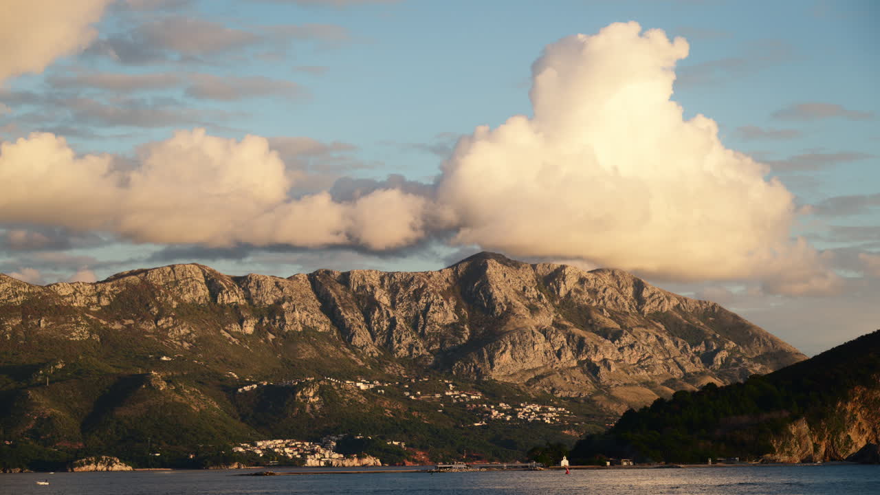 Mare con isole e costa rocciosa sotto una grande nuvola e un cielo azzurro. Budva, Montenegro