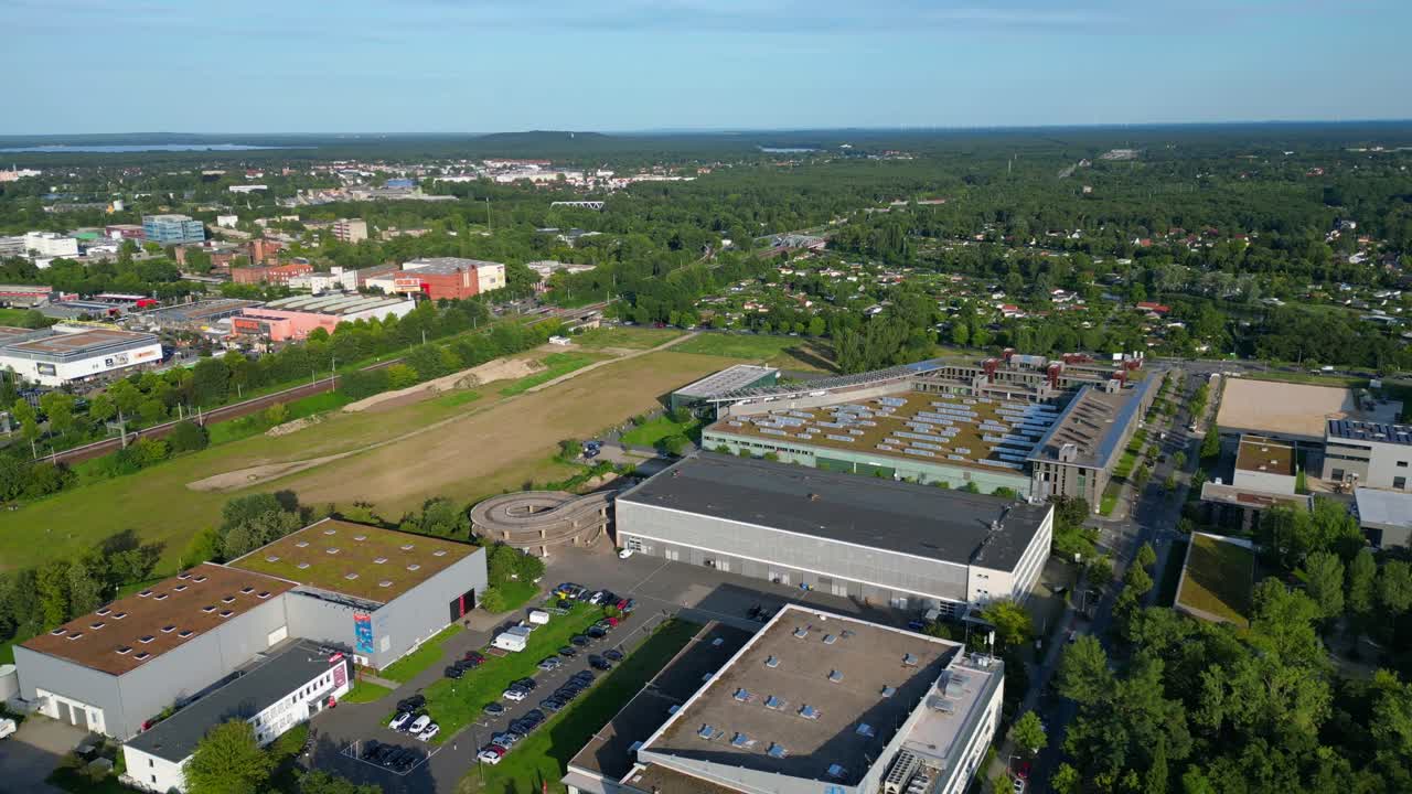 Modern film studios with offices and sound stages surrounded by trees in Berlin Adlershof, Germany. Amazing aerial view flight fly reverse overflight flyover drone